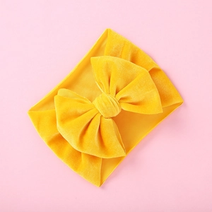 Detail of a bright yellow velvet bow headband for babies with soft ribbed fabric texture