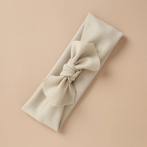 Close-up of beige knitted baby headband with a soft texture and large decorative bow