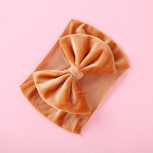 Caramel velvet bow headband for infants featuring a soft elastic band on a pink background
