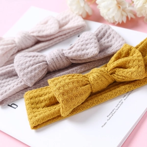 Détail de la texture gaufrée des bandeaux en tricot pour bébé avec nœud en trois coloris pastel