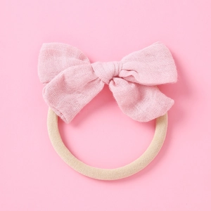 Détail du nœud en mousseline rose pâle sur un bandeau élastique pour bébé