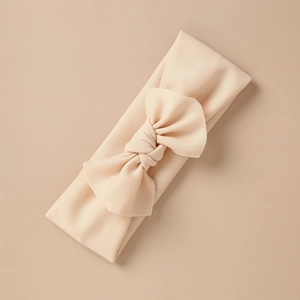 Close-up of baby headband with a large bow in soft apricot elastic ribbed knit fabric