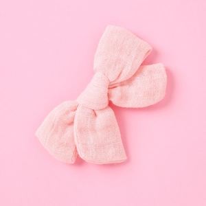 Dettaglio della molletta per capelli per neonati in mussola rosa con fiocco