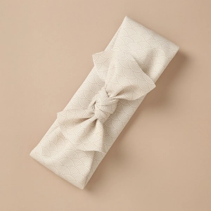 Macro detail of kids bow headband with white seigaiha wave patterns on beige fabric