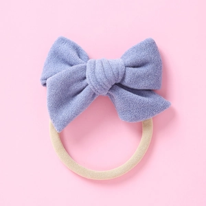 Détail d'un nœud en tricot violet et bandeau bébé en nylon beige haute élasticité