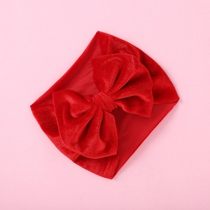 Detailed top view of a large red velvet bow headband with a wide elastic baby hair band