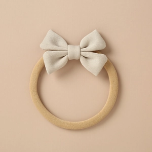 Detailed macro view of a light beige knitted bow on a high-elastic camel nylon headband