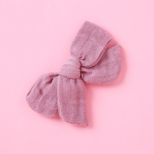 Dettaglio ravvicinato di un fiocco per capelli in mussola rosa con trama intrecciata