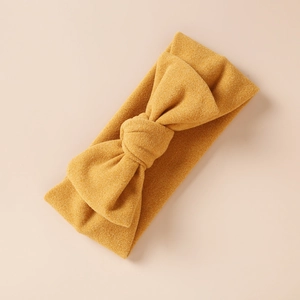 Détail d'un bandeau en cachemire jaune moutarde avec nœud et texture en maille douce