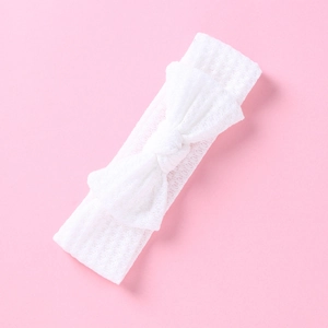Détail de la texture en dentelle blanche et du nœud sur le bandeau élastique pour bébé