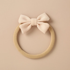 Detailed texture of high-elastic nylon baby headband with a light beige fabric bow