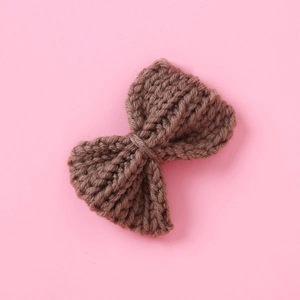 Close-up of handmade dark chocolate brown knitted wool bow hairpin with ribbed texture