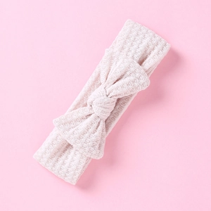 Détail d'un bandeau bébé en maille gaufre crème avec un grand nœud décoratif doux