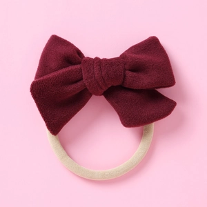 Détail du nœud en velours bordeaux sur un bandeau en nylon élastique pour bébés