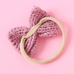 Detail view of pink knitted bow baby headband showing soft texture and elastic nylon band