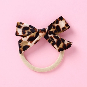 Détail d'un chouchou avec nœud en velours à imprimé léopard et élastique beige souple