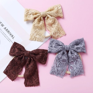 Détail de trois bandeaux bébé avec nœuds en dentelle beige, gris et brun, texture florale
