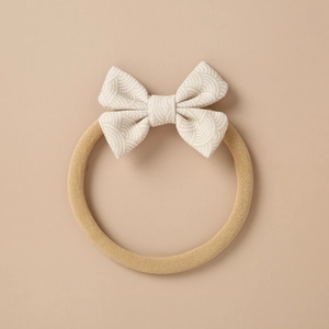 Close-up of baby bow headband showing beige wave pattern and soft nylon band