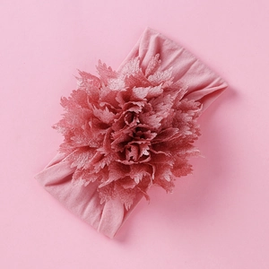 Detail eines rosa Nylon-Baby-Stirnbands mit einer großen Rüschenblume aus Stoff für Babys