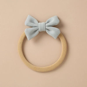 Detailed close-up of a soft light blue knitted bow attached to a tan elastic hair tie