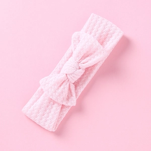 Gros plan d'un bandeau pour bébé en maille rose clair orné d'un grand nœud doux