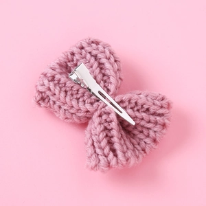 Detail of pink knitted bow hair clip showing handmade yarn texture and metal clip