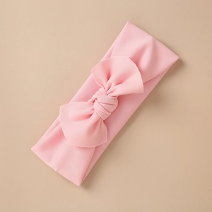 Detail of baby pink elastic knit headband featuring a large soft decorative bow
