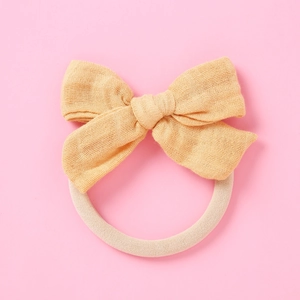 Détail du bandeau pour bébé avec nœud en gaze jaune doux et sangle en nylon élastique