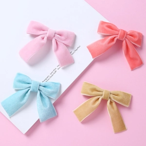 Noeuds barrettes en velours pour bébés en rose, bleu et jaune sur fond rose