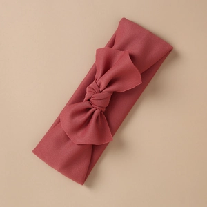 Detail of brick red ribbed knit baby headband with a large decorative bow tie