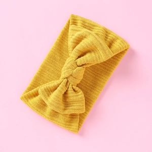 Detail eines ingwergelben Rippstrick-Stirnbands mit dekorativem Knoten-Design in der Mitte