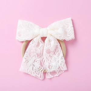 Gros plan sur un bandeau en dentelle blanche avec nœud papillon élastique pour bébé