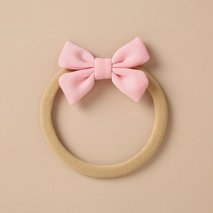 Detail of baby headband with a pink knitted bow and soft nylon elastic band for infants