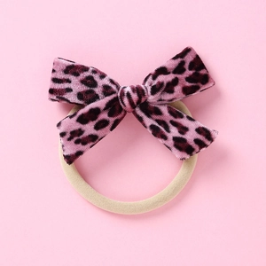 Détail de chouchou en velours léopard rose avec élastique beige pour cheveux de fille