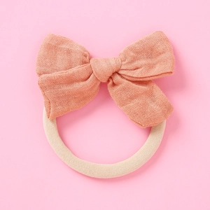 Détail du bandeau pour bébé avec nœud en gaze de bambou rose poudré et élastique en nylon