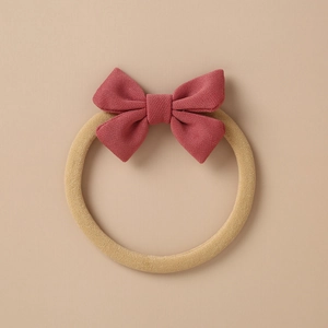 Close-up of baby elastic headband with smoky pink knitted bow on soft beige background