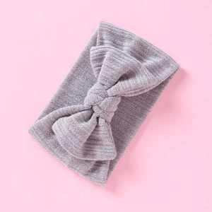 Detail eines lavendelfarbenen Strickstirnbands für Babys mit großer Schleife