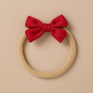 Close-up of red fabric bow hair tie with highly elastic beige band for kids and babies