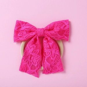 Vue détaillée du nœud en dentelle rose avec motifs floraux sur bandeau bébé élastique