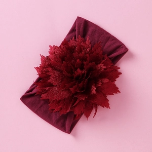 Detailansicht eines dunkelroten Nylon-Blumen-Stirnbands für Babys auf rosa Hintergrund