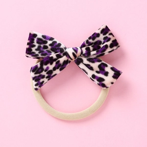 Détail d'un chouchou avec nœud en velours léopard violet et élastique beige doux