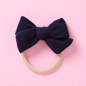 Détail de la texture du nœud en velours bleu marine avec bandeau en nylon souple pour bébé