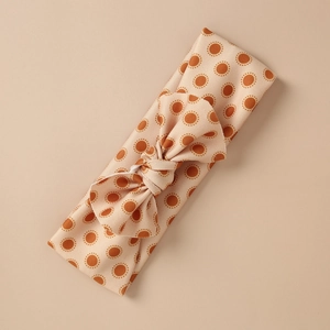 Detail view of baby bow headband with soft polka dot fabric and elastic knit texture