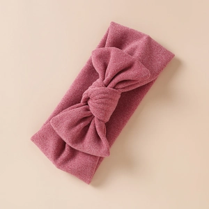 Détail d'un bandeau en maille rose pour bébé avec un grand nœud et tissu doux