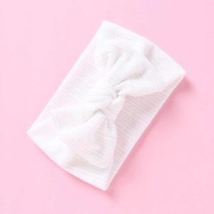 Detailaufnahme der weißen Rippstrick-Textur am elastischen Baby-Stirnband mit Schleife