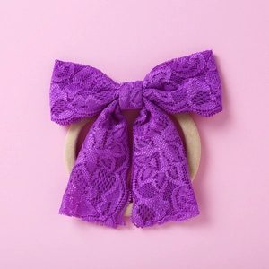 Détail d'un bandeau en dentelle violette pour filles avec texture florale sur fond rose
