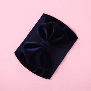 Close-up of a deep blue velvet bow headband for babies with soft textured elastic fabric