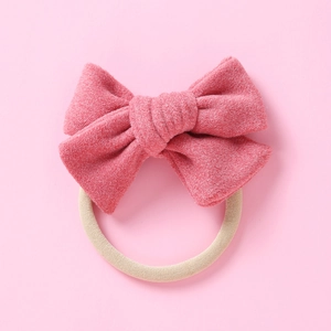 Détail d'un nœud en velours rose sur un bandeau en nylon beige pour bébés