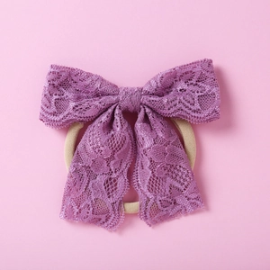 Détail du bandeau avec nœud en dentelle violette et cordon élastique sur fond rose