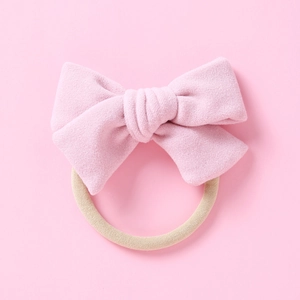 Détail d'un nœud en velours rose doux sur un bandeau pour bébé en nylon élastique